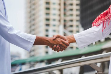 Arab Businessman shaking hands together. Teamwork business partner wear Muslim dress Shake Hands with Partnership Concept. Success UAE diversity people trust make commitment by handshake