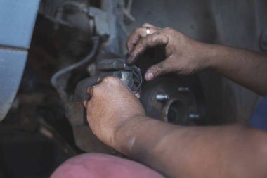 Tamirci ellerini kapayıp araba tamirhanesini tamir ediyor. Lastik değiştiriyor. Adam elleri şok emici makine araç mekanik servisini tamir ediyor. Araç bakım mühendisi.