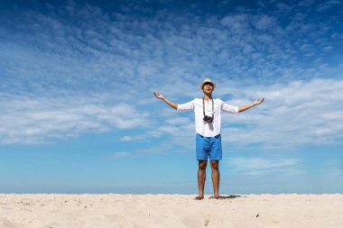 Man traveler using digital camera on summer beach blue sky take a photo. Asian Photographer man journey relax on the beach in summertime. Man backpack shooting photo asia destination holiday trip