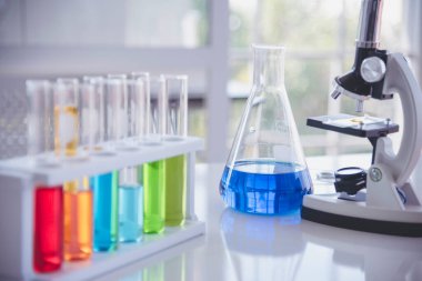 Mikroskop, cam tüpler, kimyasal deney şişesi beyaz masa bilimsel arka planı olan bilim laboratuarı kimya laboratuvarı. Renkli Sıvı Biyoloji Laboratuvarı Kimyasal Sıvı Bilimi Deneyi