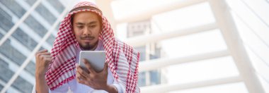 Akıllı telefon uygulaması kullanan Banner İslami adam akıllı telefon müslümanlarının modern uae şehrine odaklanma gündemini organize ediyor. Bayrak Arap erkekleri tesettürlü Müslüman resmi elbisesi giyer. Fotokopi alanı ile mutlu bir çağrı.