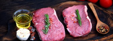 Banner Raw bifteği organik malzeme ahşap masa arkasında arka planda biberiye, tuz, sarımsak, domates yağı ile birlikte. Biftek için ahşap tabakta biftek ve fotokopi alanı.