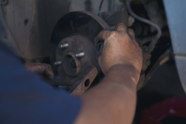 Tamirci ellerini kapayıp araba tamirhanesini tamir ediyor. Lastik değiştiriyor. Adam elleri şok emici makine araç mekanik servisini tamir ediyor. Araç bakım mühendisi.