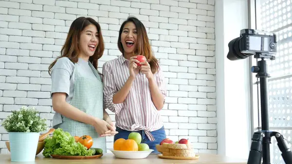 Asyalı vlogger canlı yayında sağlıklı beslenme tarzı hakkında yorum yapıyor. İki genç bayan arkadaş blogcu mutlu bir yaşam tarzı sunuyor. Sebze, meyve, vejetaryen ürünleri nasıl yenir. İki kadın sosyal medya vlog 'undan bahsediyor