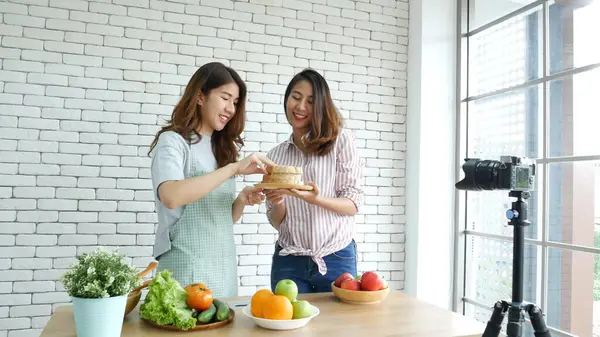 Asyalı vlogger canlı yayında sağlıklı beslenme tarzı hakkında yorum yapıyor. İki genç bayan arkadaş blogcu mutlu bir yaşam tarzı sunuyor. Sebze, meyve, vejetaryen ürünleri nasıl yenir. İki kadın sosyal medya vlog 'undan bahsediyor