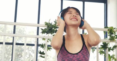 Güzel kadın gülümse, müziği dinle. Yoga yapan kadın spor kıyafetleri giyer yoga minderinin üstüne oturur spor salonunda egzersiz yapar. Mutlu güzel kadınlar yerde dans ederler kulaklık kullanırlar müzik dinlerler sağlık yaşam tarzı