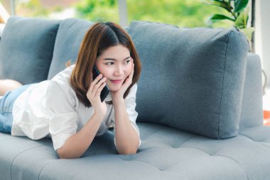 Gülümseyen Asyalı kadın elinde e-ticaret alışverişi internet sitesi Reading Online Article, Blog, vlog ile akıllı telefon tutuyor. Genç kadının elleri telefon teknolojisi yaşam tarzını tutuyor. Akıllı telefon kullanan kadın.