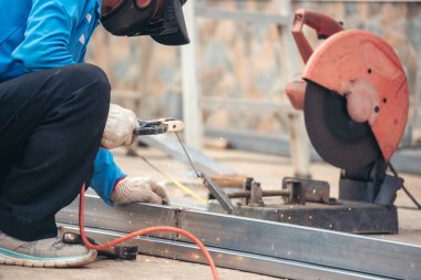 Erkek elleri koruyucu eldiven giyer. Alev metali, ateş demiri atölyesini keser. Çilingir kaynak makinesi kullanmış. Metal işlemleri kesmiş. Kaynak makinesi kullanan inşaat işçisi elleri demir gibi kıvılcım saçıyor.