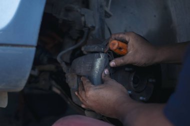 Tamirci ellerini kapayıp araba tamirhanesini tamir ediyor. Lastik değiştiriyor. Adam elleri şok emici makine araç mekanik servisini tamir ediyor. Araç bakım mühendisi.