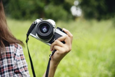 Eller yukarı, Asyalı kadınlar DSR dijital kamera klasik film tarzına bakıyor. Fotoğraf çekin. Profesyonel bayan fotoğrafçı dışarıdaki resme bakar. Yeşil doğa parkında fotoğraf çeken genç bir kadın.