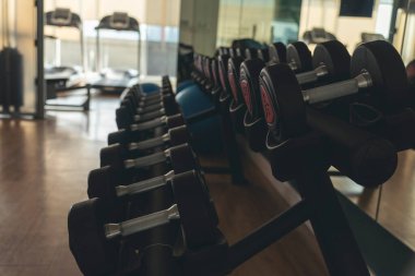 Dambıllar fiziksel halter kaldırma aletlerini rafa kaldırır. Vücut geliştiren kas geliştiren spor kulüpleri vücut egzersizleri yapıyor. Spor salonunda Black Metal dambıllar.