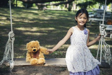 Yeşil Park 'ta oyuncak ayıya sarılırken mutlu çocuk. Oyuncak ayı, küçük çocuklar için en iyi arkadaş tatlı kız. Otizm mutlu bir şekilde oyun bahçesinde birlikte oynayarak mutlu bir aile sevgisi ve sıcacık kucaklaşmayı hisseder.