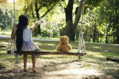 Yeşil Park 'ta oyuncak ayıya sarılırken mutlu çocuk. Oyuncak ayı, küçük çocuklar için en iyi arkadaş tatlı kız. Otizm mutlu bir şekilde oyun bahçesinde birlikte oynayarak mutlu bir aile sevgisi ve sıcacık kucaklaşmayı hisseder.