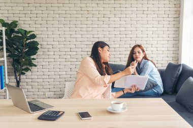 İki iş kadını takım toplantısı şirket masasında dizüstü bilgisayarla yapılıyor. Finansal grafik grafikleri okuyan iki genç kadın pazarlama verilerini analiz etmeyi planlıyor. Asyalı ekip çalışma bürosu.