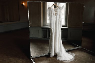 Gelinlik büyük bir salonda askıda asılı.