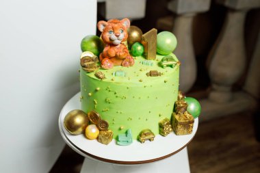 Bir yaşındaki bir bebek için kaplan heykelciği olan tatlı yeşil pasta.