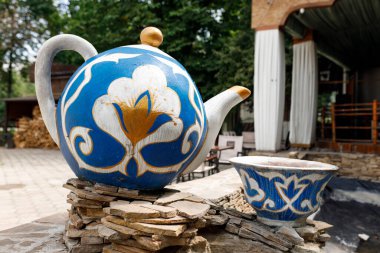 Çaydanlık şeklinde bir heykel ve desenli mavi bir fincan.