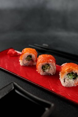 a classic Philadelphia roll, featuring shrimp and salmon, takes center stage against a sleek black backdrop. It's a mouthwatering representation of Japanese cuisine