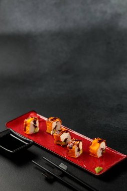 Lezzetli bir kar yengeci ile bir mami rulosu siyah bir arka plana karşı zarif bir şekilde sergilenir, Japon mutfağının özünü temsil eder.