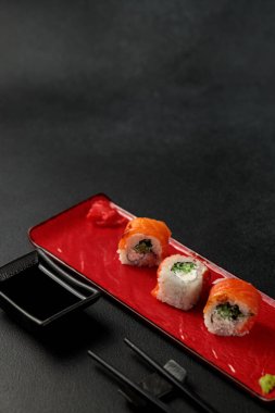 a classic Philadelphia roll, featuring shrimp and salmon, takes center stage against a sleek black backdrop. It's a mouthwatering representation of Japanese cuisine