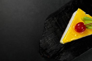 Kirazlı limonlu cheesecake, parlak siyah arka planda. Ağız sulandıran görsel tedavi tatlı aşıkları ve mutfak sunumları için mükemmel.