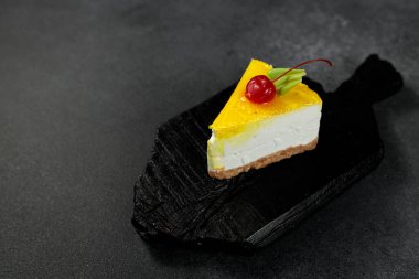 Kirazlı limonlu cheesecake, parlak siyah arka planda. Ağız sulandıran görsel tedavi tatlı aşıkları ve mutfak sunumları için mükemmel.