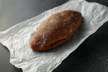 Bu büyüleyici görüntü, parşömen kağıdının üzerinde duran ev yapımı kuru üzümlü ekmeği gösteriyor. Mutfak yayınları, yemek blogları ya da pastane promosyonları için mükemmel. Sıcak ve konforlu bir ortam yayıyor. Seyircileri basit bir zevkten zevk almaya davet ediyor.