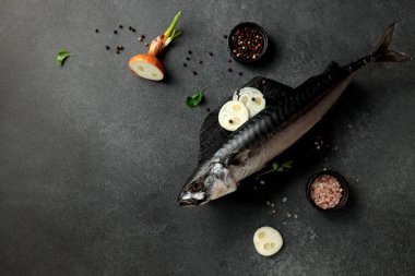 Pürüzsüz siyah bir kesme tahtasının üzerinde koyu bir arka planda füme uskumrunun göz kamaştırıcı görüntüsü. Yemek meraklıları ve menü tasarımcıları için mükemmel. Bu resim gurme deniz ürünlerinin cazibesini yakalar.