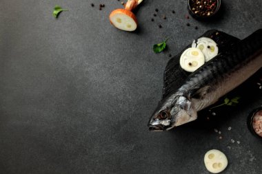 Pürüzsüz siyah bir kesme tahtasının üzerinde koyu bir arka planda füme uskumrunun göz kamaştırıcı görüntüsü. Yemek meraklıları ve menü tasarımcıları için mükemmel. Bu resim gurme deniz ürünlerinin cazibesini yakalar.