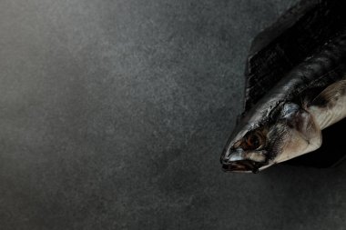 Pürüzsüz siyah bir kesme tahtasının üzerinde koyu bir arka planda füme uskumrunun göz kamaştırıcı görüntüsü. Yemek meraklıları ve menü tasarımcıları için mükemmel. Bu resim gurme deniz ürünlerinin cazibesini yakalar.