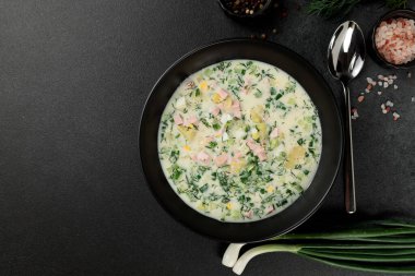 Soğuk çorba, salatalık, sosis, çorba ve ekşi krema siyah bir tabakta. Geleneksel bir yemek okroshka