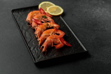 Siyah arka planda büyük pişmiş kral karidesleri. Limon dilimleri