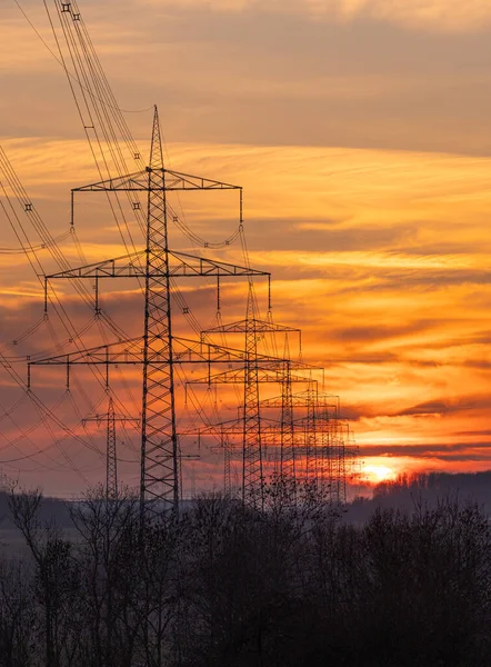 Energy Distribution Network - Electricity Pylons against Orange and Yellow Sunset