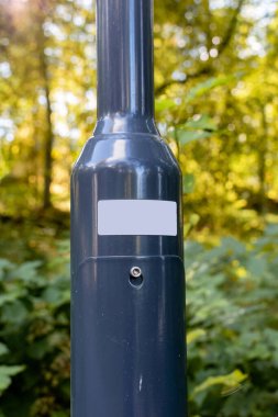 Metalik ışık direğindeki boş beyaz etiketi kapat ve arka planda orman olsun.