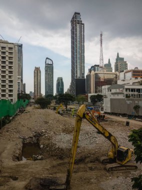 İnşaat alanında arka planda gökdelenler olan kazıcılar