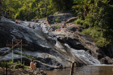 Mo Paeng Waterfall in Pai, Thailand with tourists spending time and swimming in the pool.
