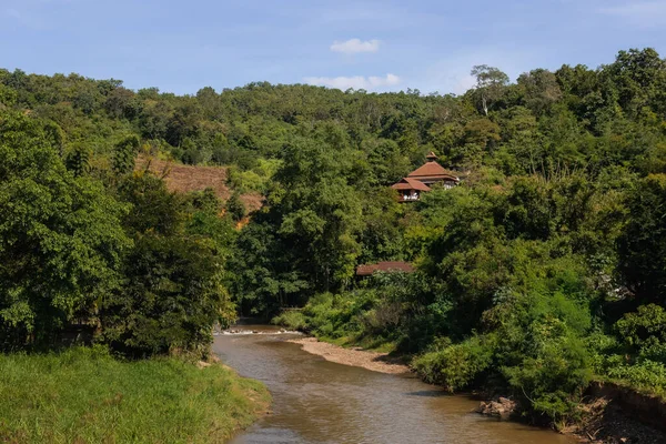River in the jungle with house up on the hill in Thailand