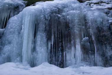Clear blue ice wall on top of a rock in Lapakisto Nature reserve, Lahti, Finland
