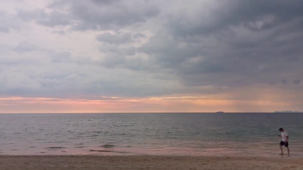 男は携帯電話ロングビーチ カランタ タイの日没前に水の端に沿って歩いて使用しています 2022年12月2日 — ストック動画