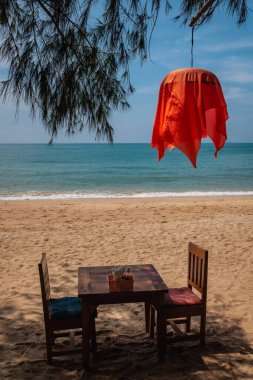 Wooden restaurant table and two chairs on a tropical beach with a red lantern in Ko Lanta, Krabi, Thailand