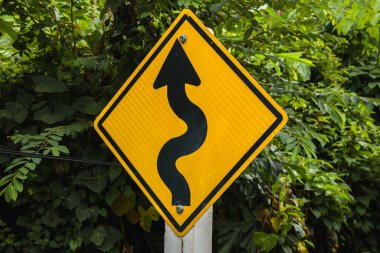 Sarı kıvrımlar uyarı işareti ve arka planda yeşil yapraklar. Ko Lanta, Krabi, Tayland.