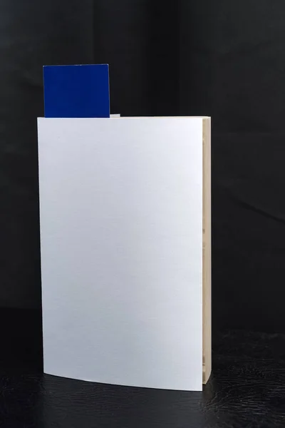 Blank white book cover template with blue bookmark on top of the black speaker cabinet . Clipping path.