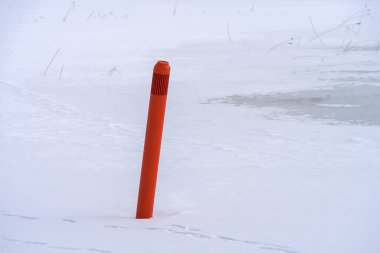 Red navigational spar buoy on a frozen lake in Hollola, Finland