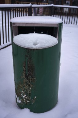 Karla kaplı yeşil metal çöp tenekesi. Hameenlinna, Finlandiya.