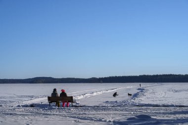 Bir kış günü Vesijarvi Gölü 'nün buzundaki insanlar. Vaaksy, Asikkala, Finlandiya.
