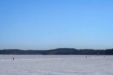 İnsanlar kışın Vesijarvi Gölü 'nün buzunda yürüyorlar. Vaaksy, Asikkala, Finlandiya.