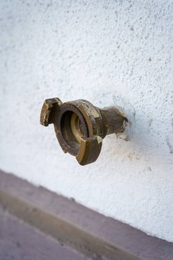 Beyaz beton bir duvarda açık deniz hortumu konnektörü.