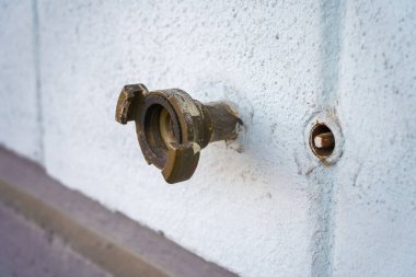 Beyaz beton bir duvarda açık deniz hortumu konnektörü.