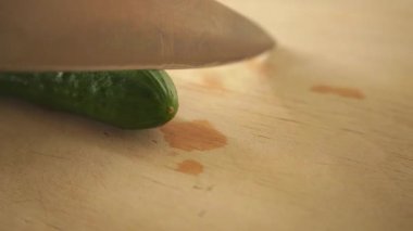 Yakından bıçakla yeşil salatalık doğramak.