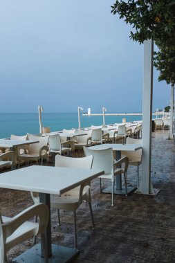 Boş bir deniz kenarı Akdeniz restoranında beyaz masalar..